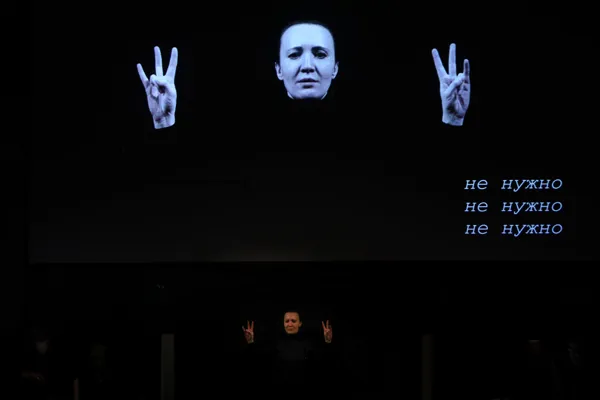 На экране Рахманиновского зала: перформер Юлия Мигунова исполняет в сурдопереводе пьесу Александра Хубеева «Не выходи из комнаты» (2020) для перформера, ансамбля, электроники и видео